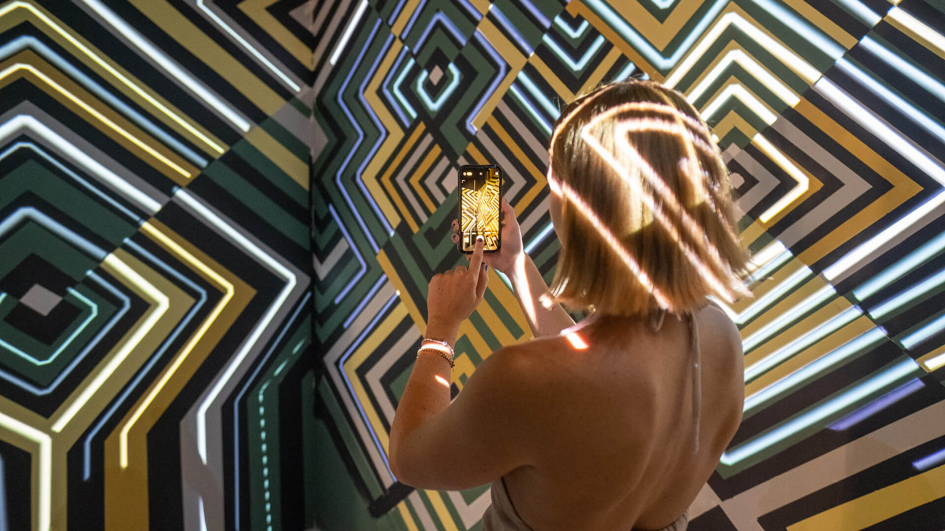 a woman taking a photo on a smart phone within an Art of Mixology installation as part of an experiential brand activation for Kingpin 