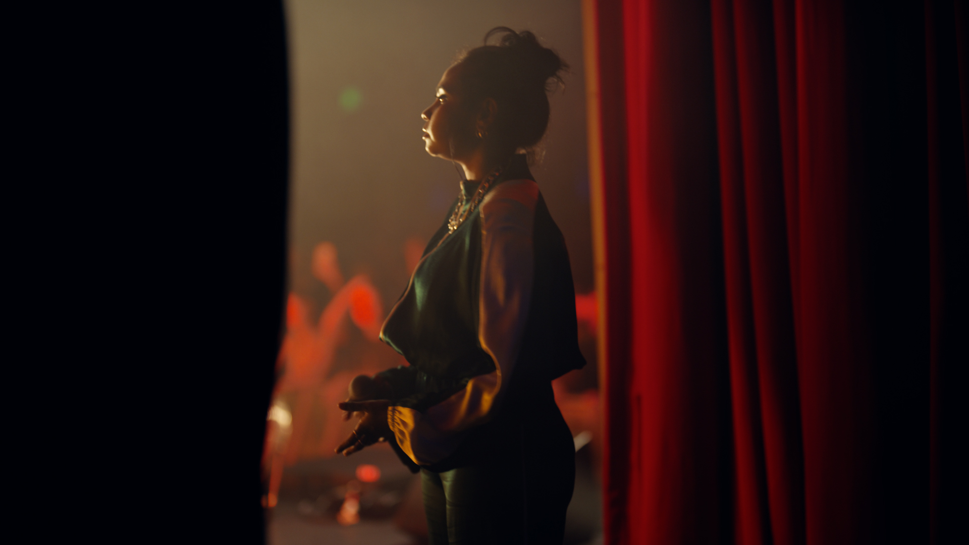 Still from google Helpfulness campaign TVC featuring a. young woman flanked by stage curtains on stage