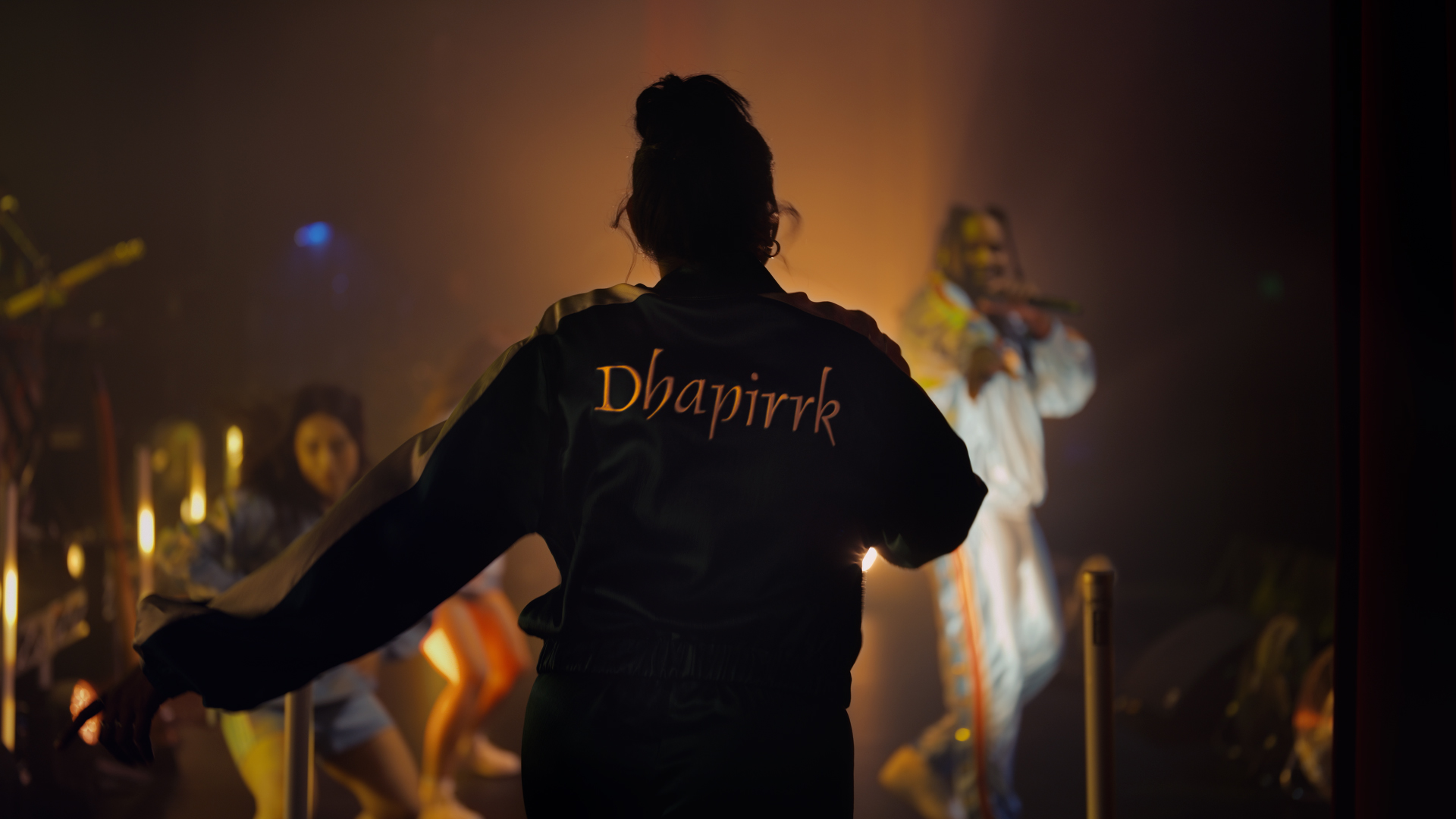 Still from google Helpfulness campaign TVC featuring Baker Boy performing while a young woman in an embroidered jacket looks on