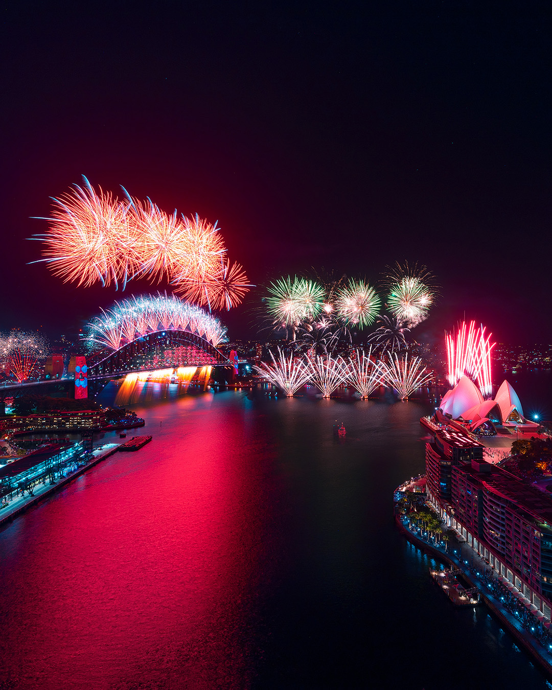Wide shot of animated visuals projected onto the Sydney Harbour Bridge, flanked by fireworks, for New Years Eve 2021